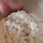 Man rinses rice in a bowl of water