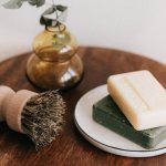 Two bars of craft soap on a wooden table with other toiletries