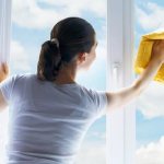 Woman washing a window in sunny weather